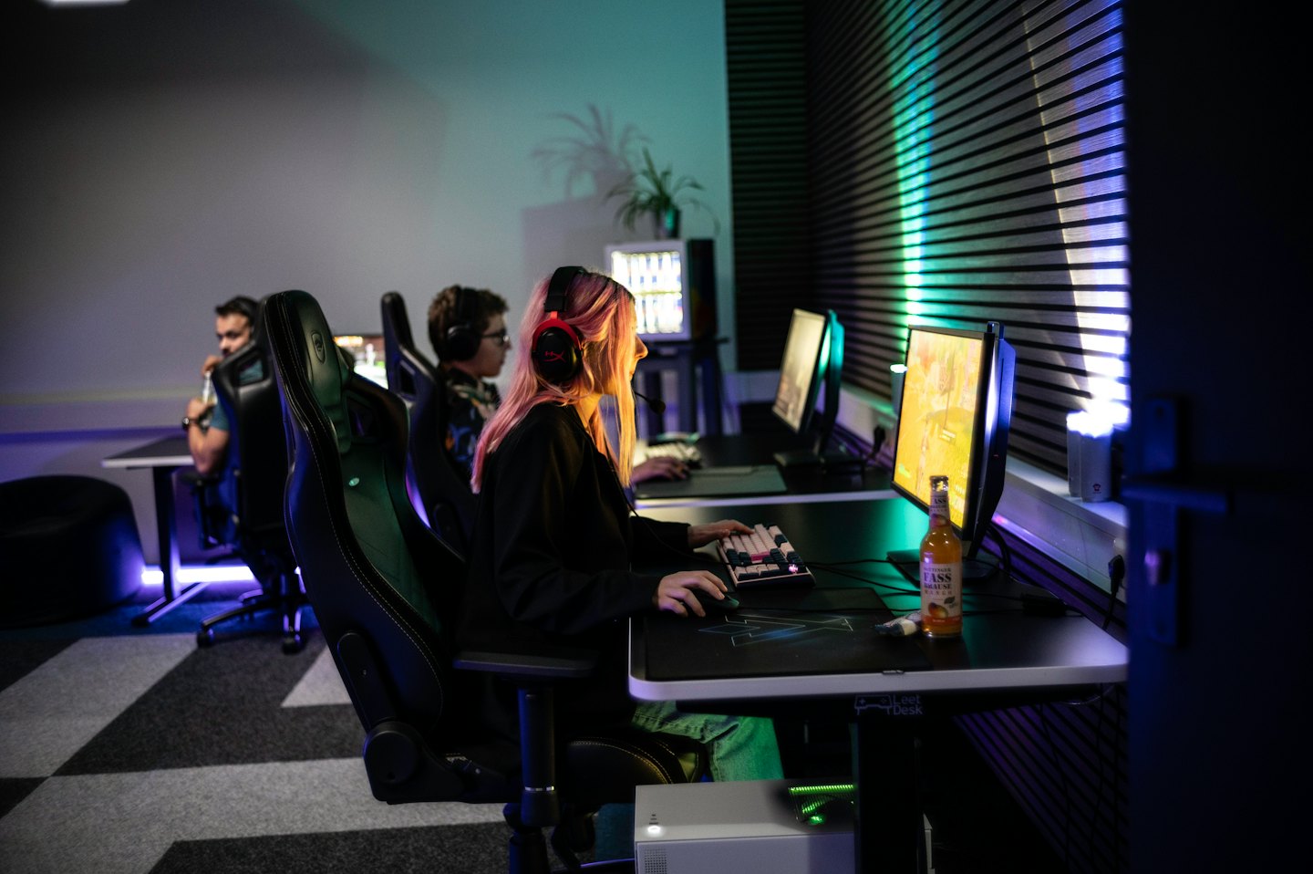 Jauni suaugusieji, intensyviai susikaupę į kompiuterinius žaidimus e-sporto arenoje.