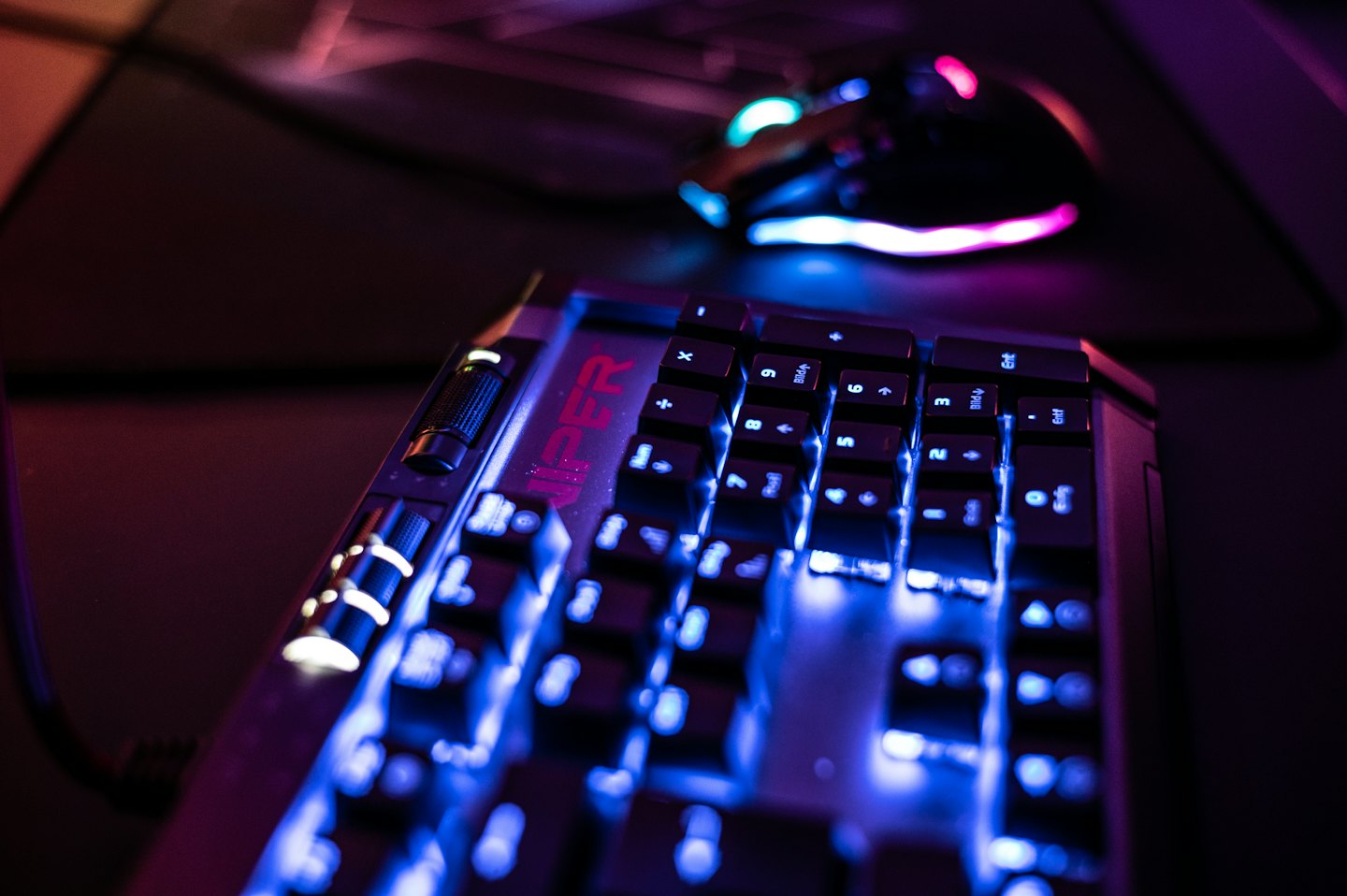 RGB apšviesta žaidimų klaviatūra ir pelė ant stalo.